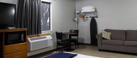 A hotel room with a bed, a desk, a television, a microwave, and a window with curtains.