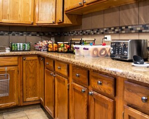 A kitchen with wooden cabinets, a granite countertop, and various kitchen appliances including a toaster and a coffee maker.