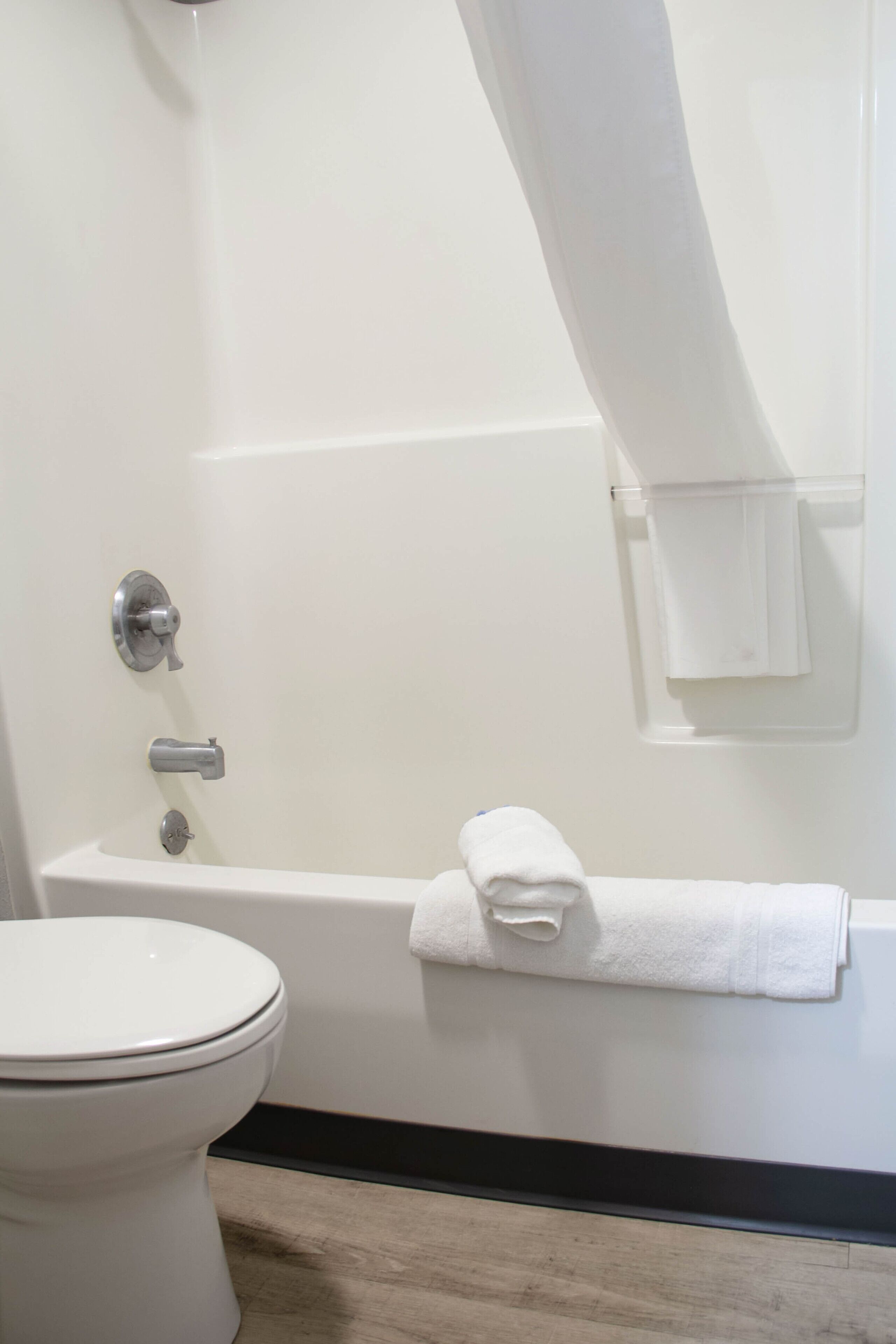 Een badkamer met een wit toilet, een badkuip met een handdoek en een douchegordijn.