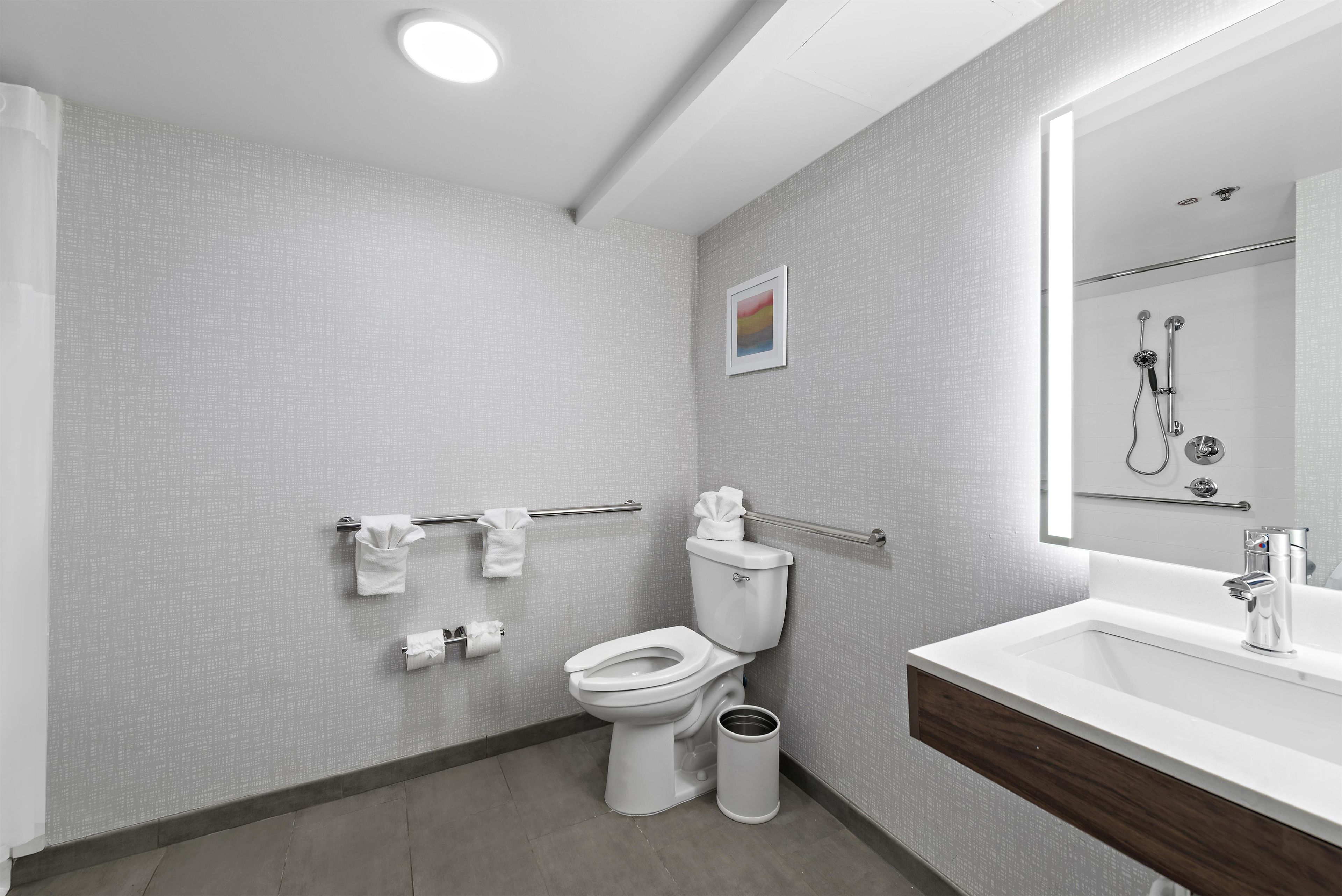 A modern bathroom with a toilet, bidet, hand dryer, and a sink with a mirror.