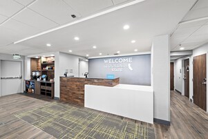 A reception area with a 'WELCOME TO THE GOLDEN STATE' sign, a counter, and a coffee machine.