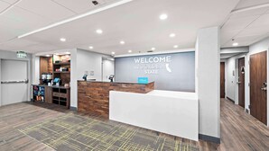 A hotel reception area with a 'Welcome the Golden State' sign, a reception desk, a coffee machine, and a self-service kiosk. - Hampton Inn by Hilton Los Angeles Airport LAX (Inglewood)