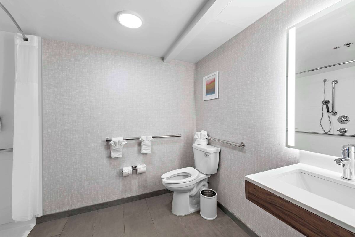 A modern bathroom with a toilet, sink, and shower.