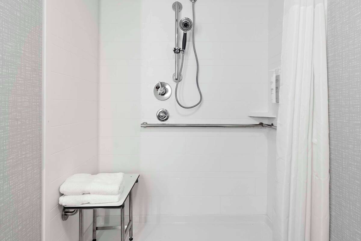 A walk-in shower with a glass door, a towel rack, and a showerhead.