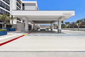 A modern building entrance with a 'Welcome' sign, clear sky, and parking area with blue handicapped parking spaces. - Hampton Inn by Hilton Los Angeles Airport LAX (Inglewood)