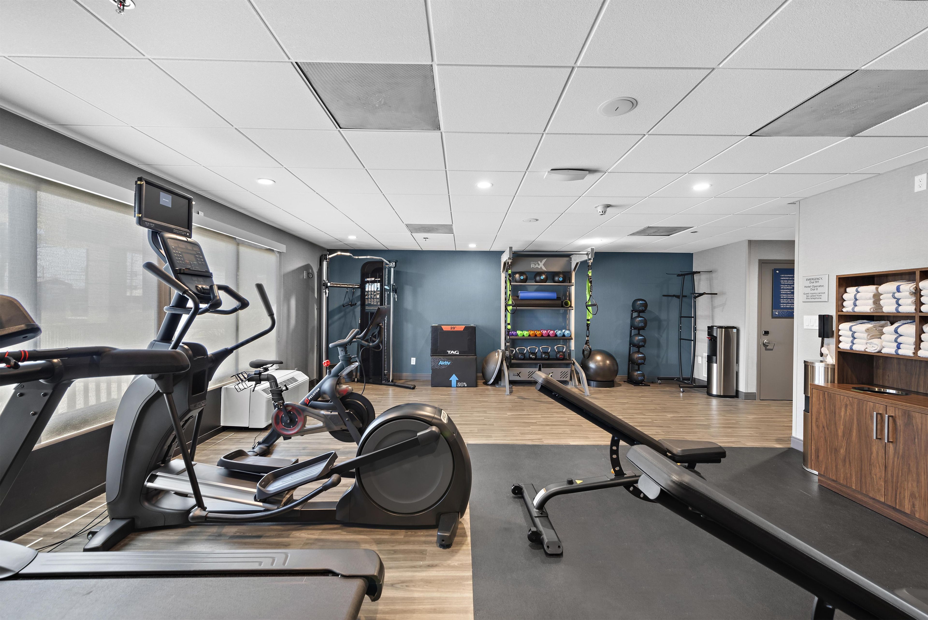 Ett gym med träningsutrustning, en vattenautomat och utsikt över staden.
