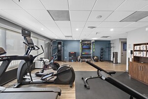A gym with exercise equipment, a water dispenser, and a view of the city.
