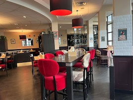 Un restaurante con sillas rojas, una zona de bar y una barra.
