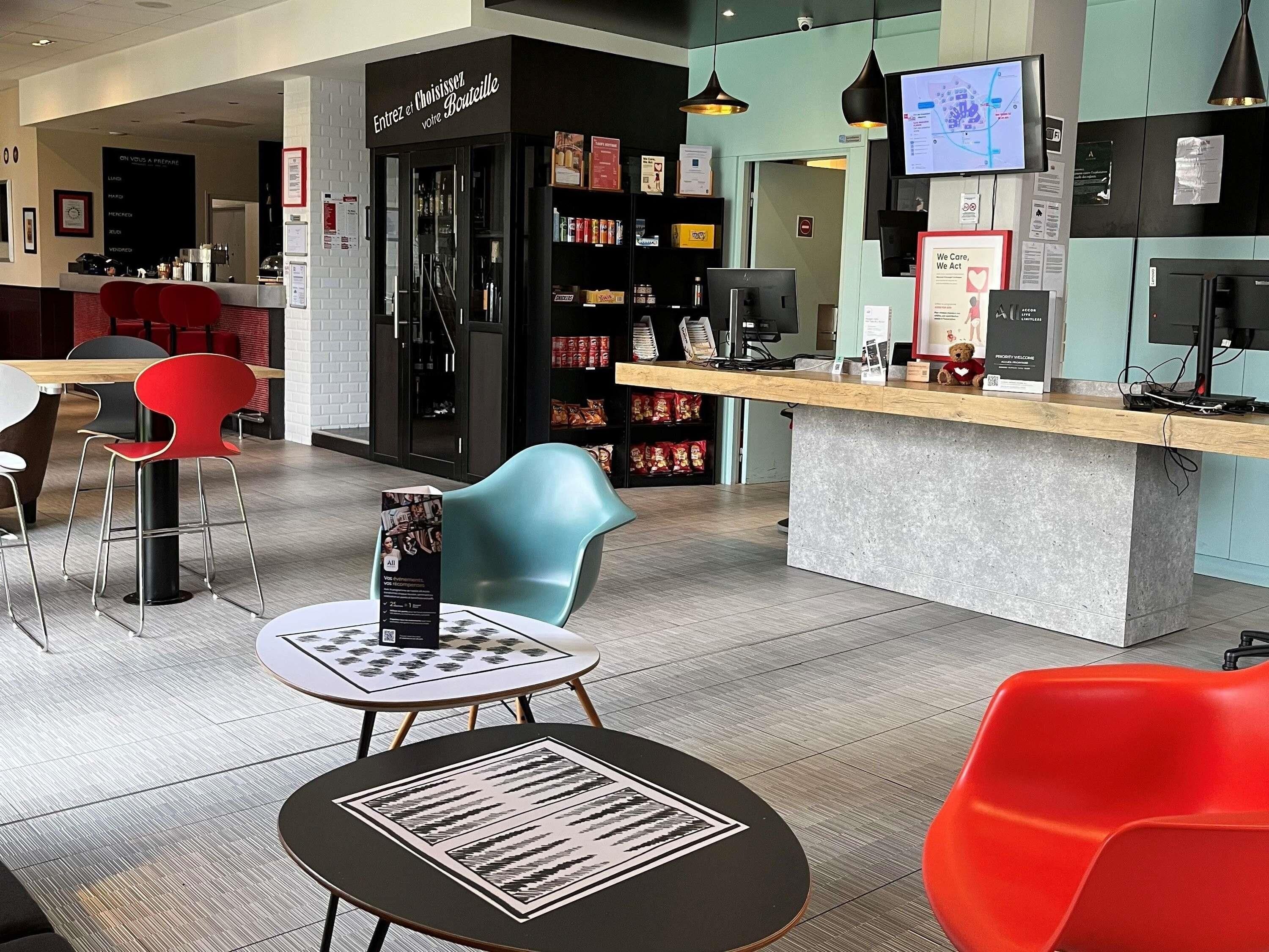 A modern interior with a reception desk, seating area, and a counter with various items.