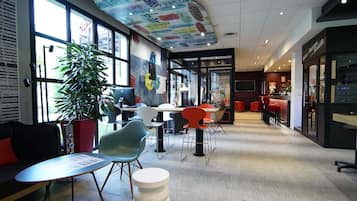 Ein modernes Interieur mit gewölbter Decke, großen Fenstern und einer Sitzecke mit Tischen und Stühlen.