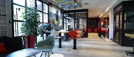A modern interior with a curved ceiling, large windows, and a seating area with tables and chairs.