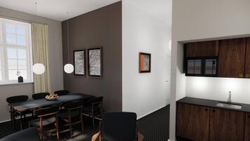 A modern hotel room with a dining area, a kitchen with a built-in sink, and artwork on the walls.