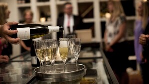 Uma pessoa servindo vinho em copos em um balcão de bar.