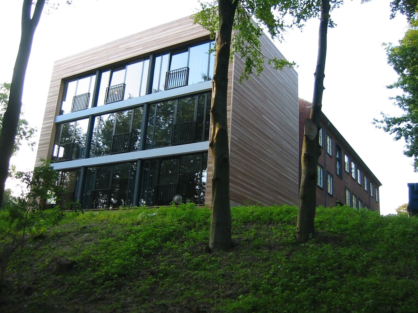 Ein modernes Gebäude mit Glasfassade, großen Fenstern und flachem Dach.
