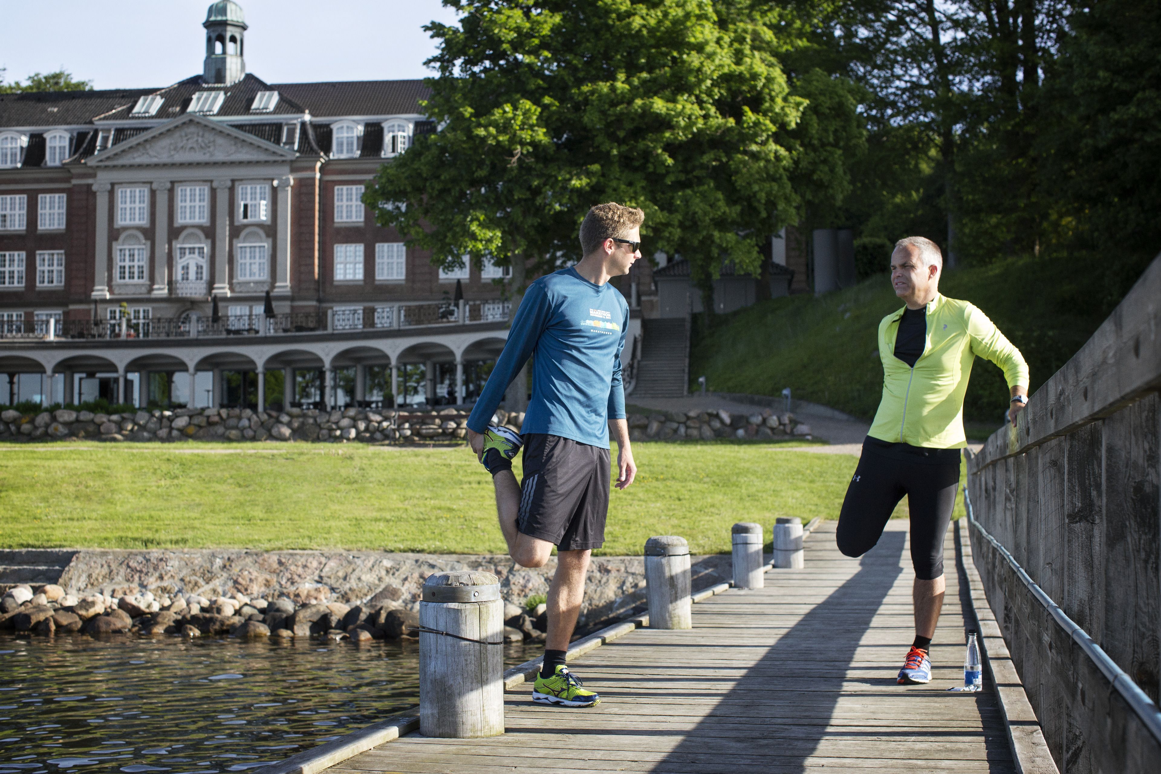 A wooden boardwalk by a body of water with a historic building in the background.