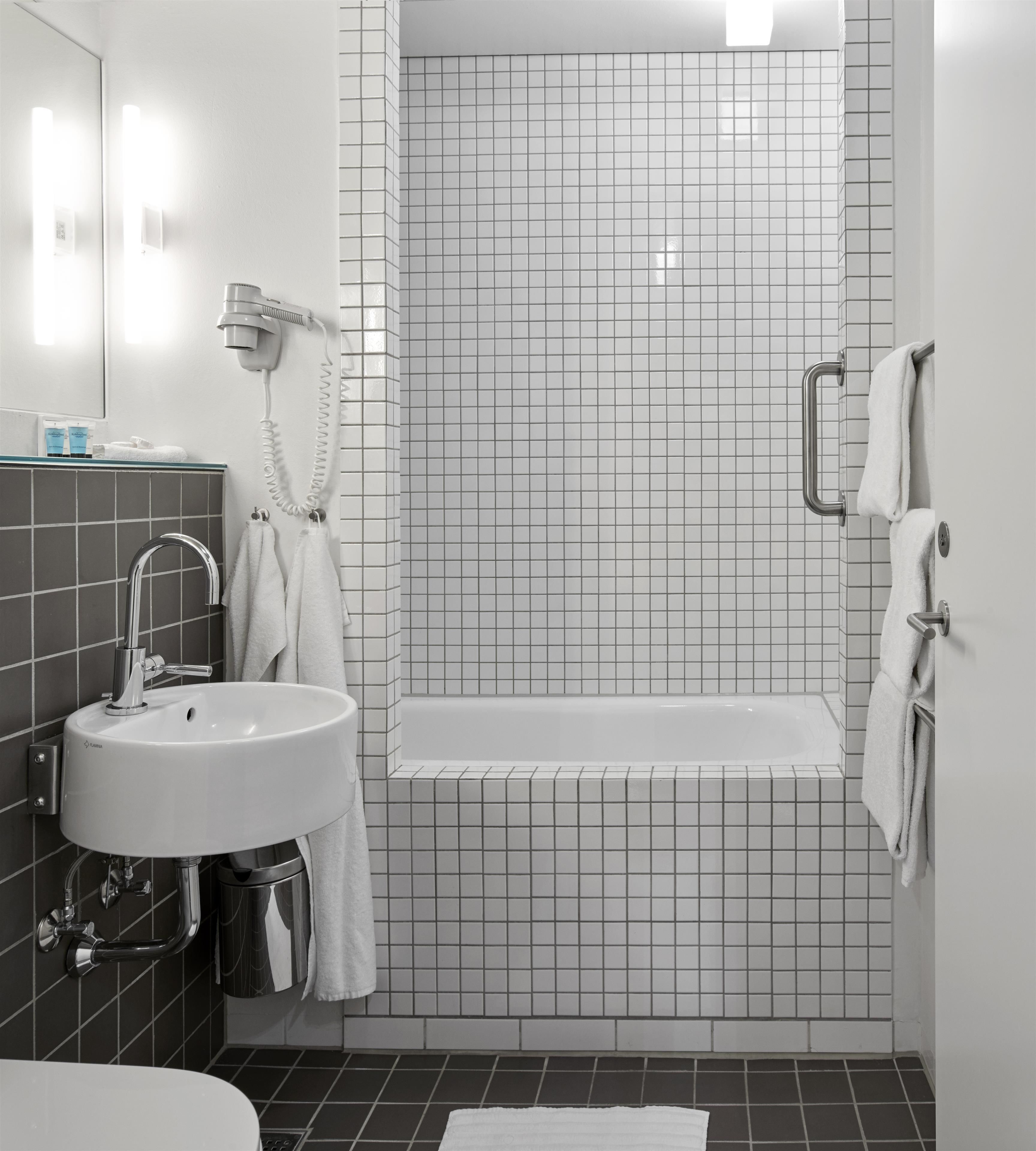 A modern bathroom with a sink, mirror, and a shower area with tiled walls.
