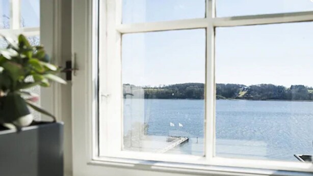 Quarto com uma janela grande com vista para a água e um cais.