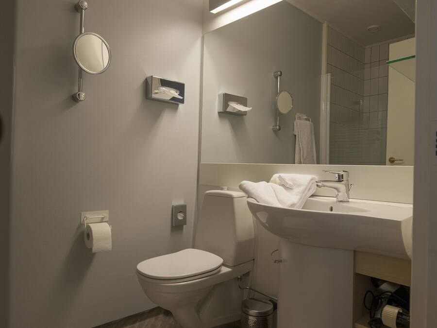 A modern bathroom with a toilet, sink, mirror, and towel rack.