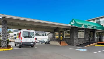Un edificio con toldo verde que dice "Quality Inn" y fachada de piedra.