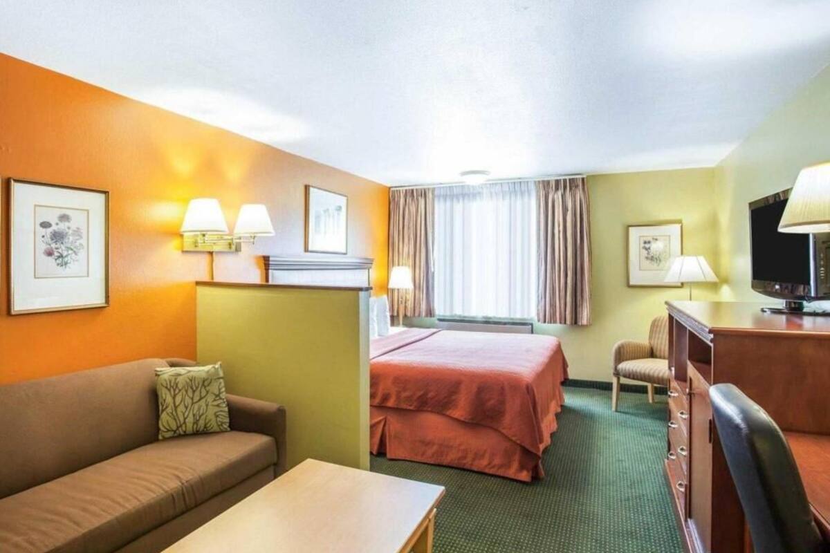 Une chambre d’hôtel comprenant un lit, un bureau, une chaise, un canapé et deux lampes.