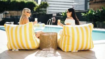 Una piscina al aire libre, sombrillas, sillones reclinables de piscina