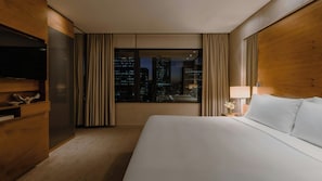 A hotel room with a large bed, a television, a desk with a lamp, and a view of the cityscape at night. - InterContinental Brisbane by IHG (Brisbane)