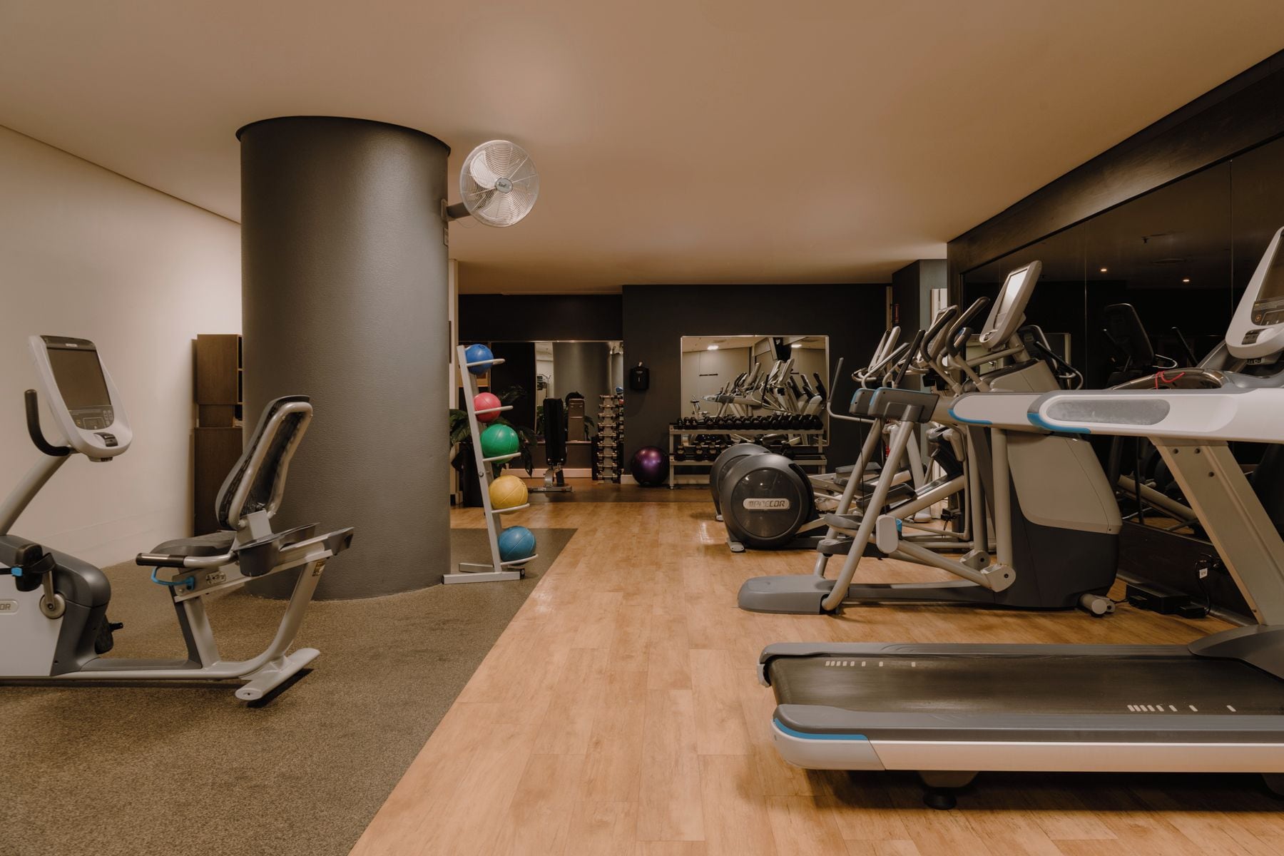A gym with treadmills, elliptical machines, and exercise balls.