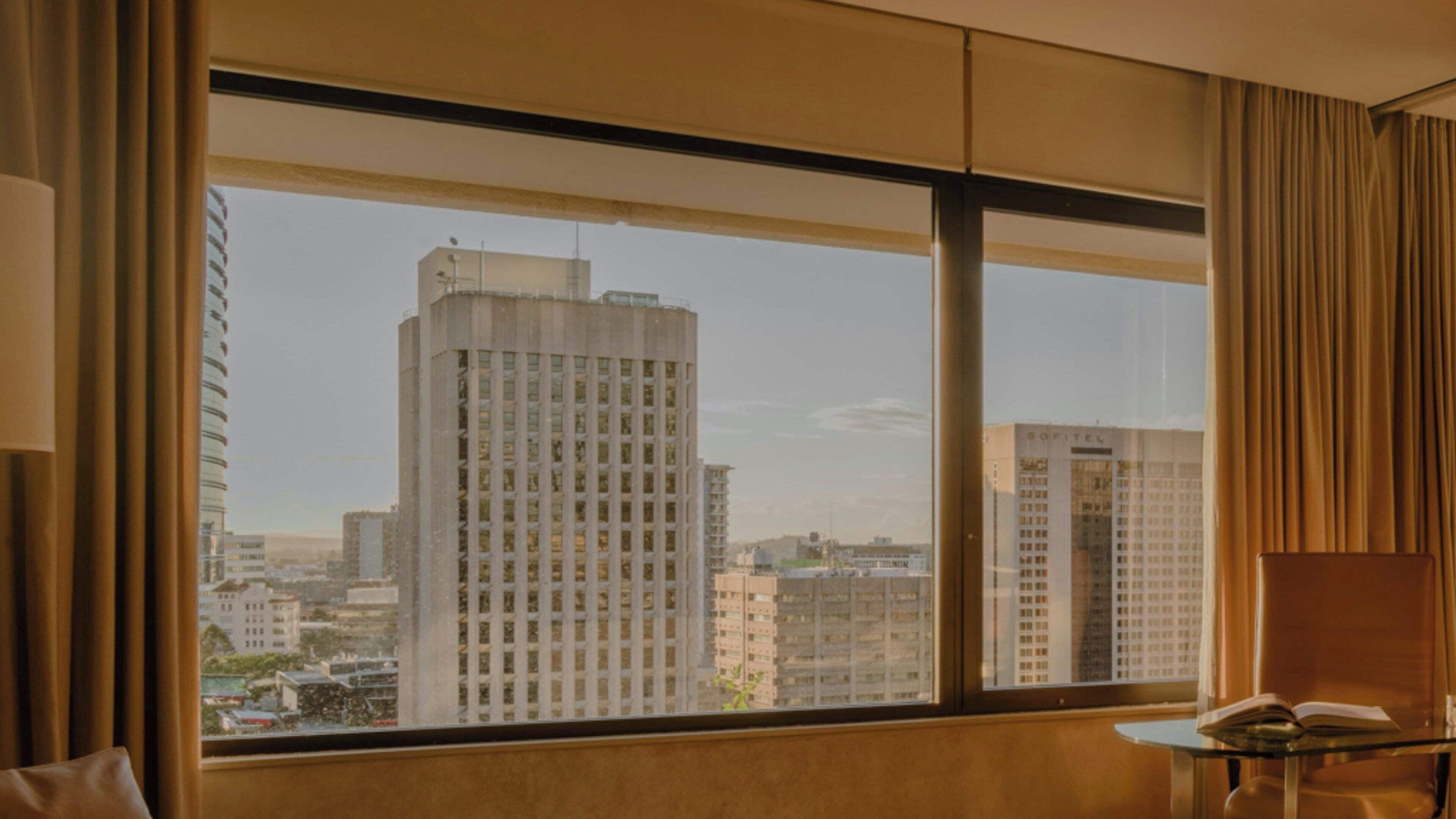 A hotel room with a large window offering a view of high-rise buildings.