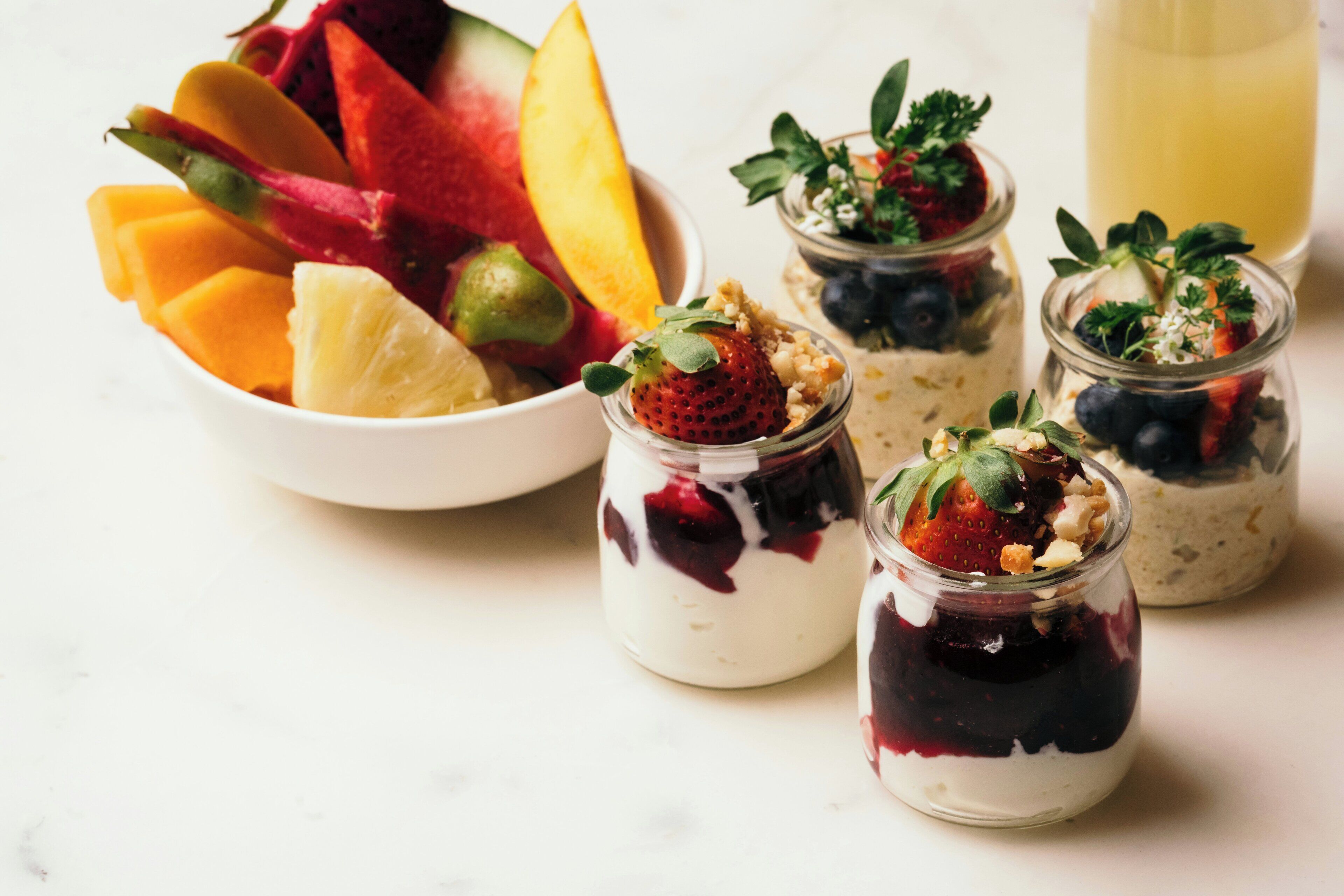 A variety of fruits and a glass of juice on a table.