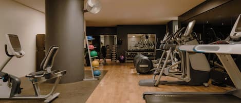 A gym with treadmills, elliptical machines, and exercise balls.