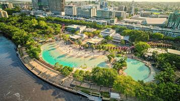 Un complejo turístico frente al mar con una gran piscina, rodeado de exuberante vegetación y edificios modernos.
