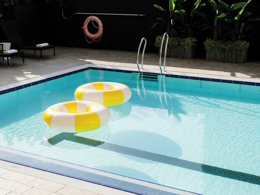 Una piscina al aire libre, sombrillas, sillones reclinables de piscina