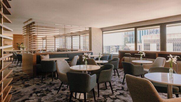 A modern hotel lobby with round tables, comfortable seating, and large windows offering city views. - InterContinental Brisbane by IHG (Brisbane)
