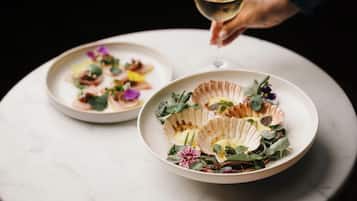 Two plates of food on a table with a glass of white wine.