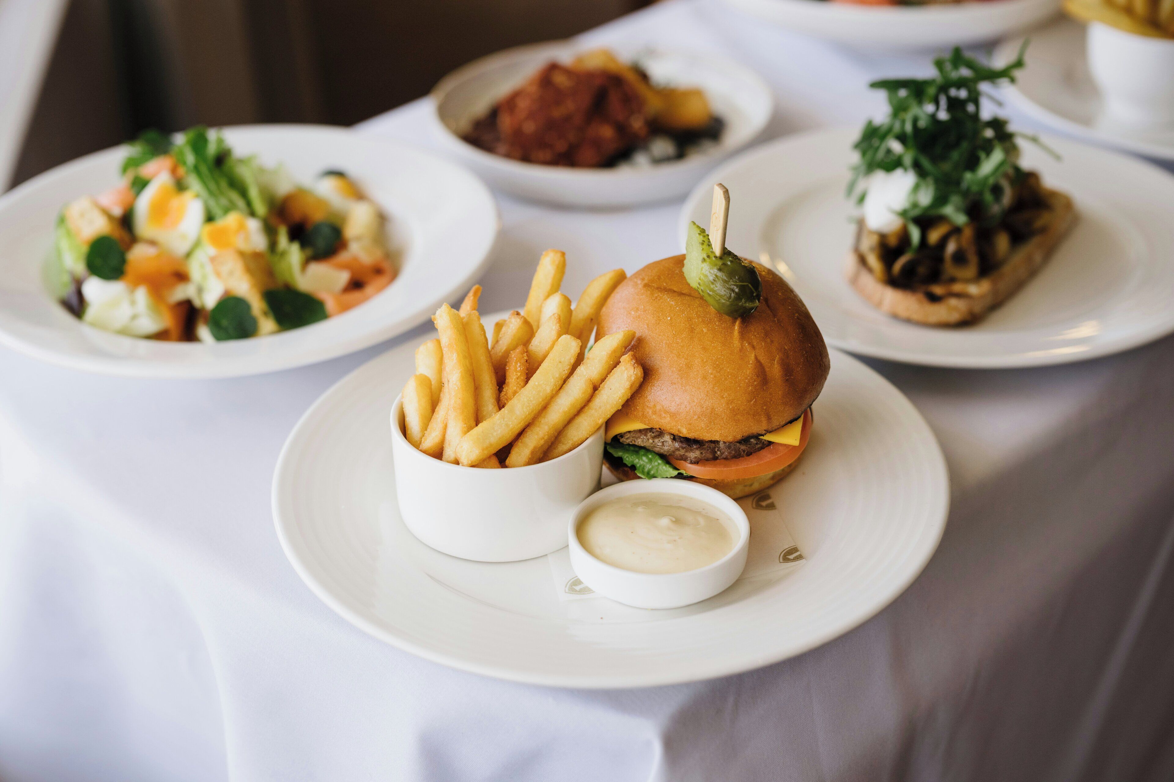A table with a burger, fries, and a salad.