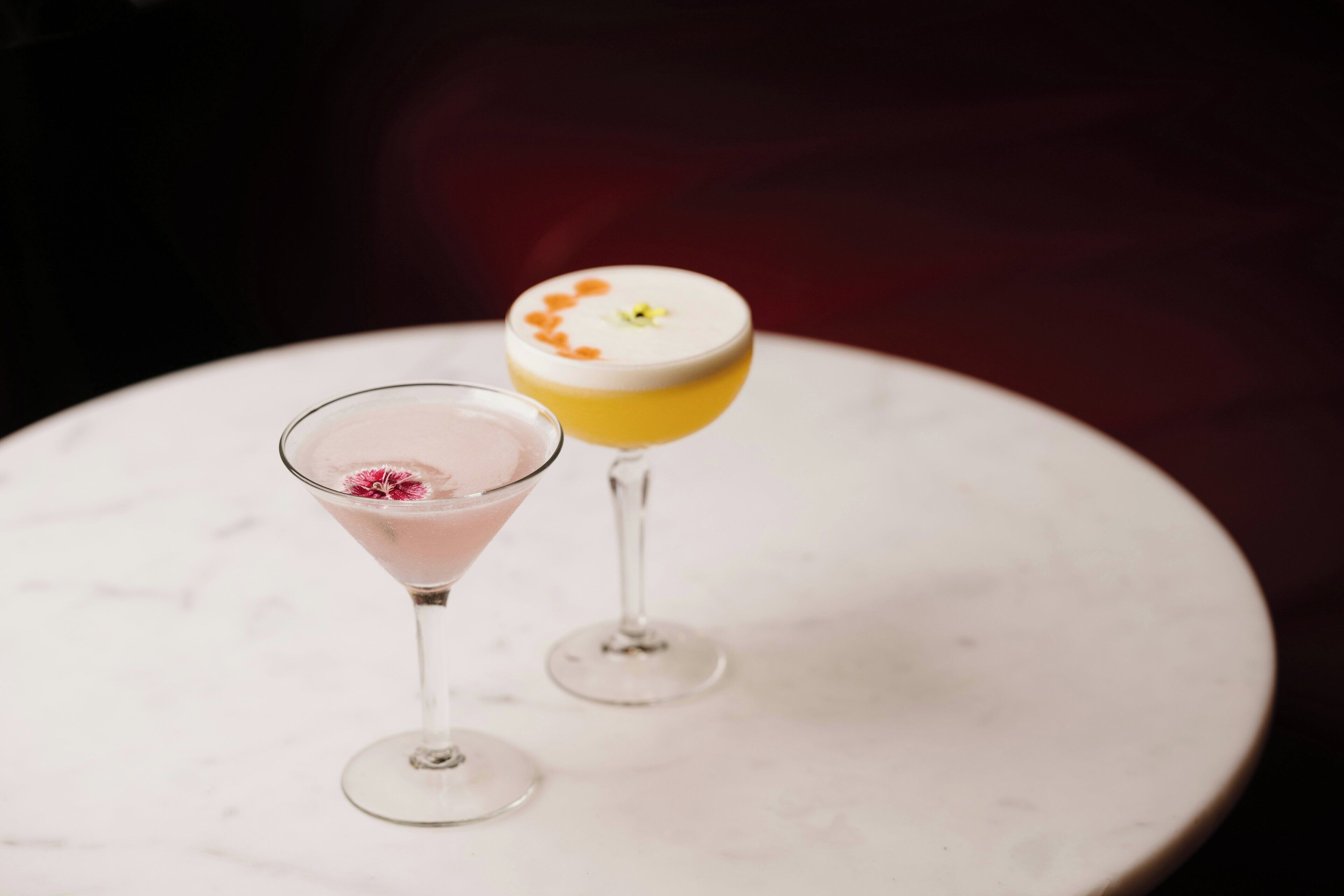 Two cocktails on a white marble table.