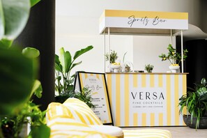 Un bar llamado 'Versa' con un diseño a rayas amarillas y blancas, que muestra un menú y una caja registradora.
