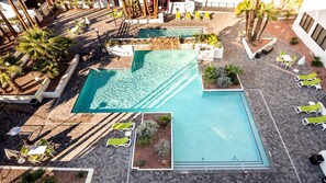 A rooftop pool area with multiple sections, surrounded by lounge chairs and palm trees. - Holiday Inn Phoenix-Mesa/Chandler by IHG (Mesa)