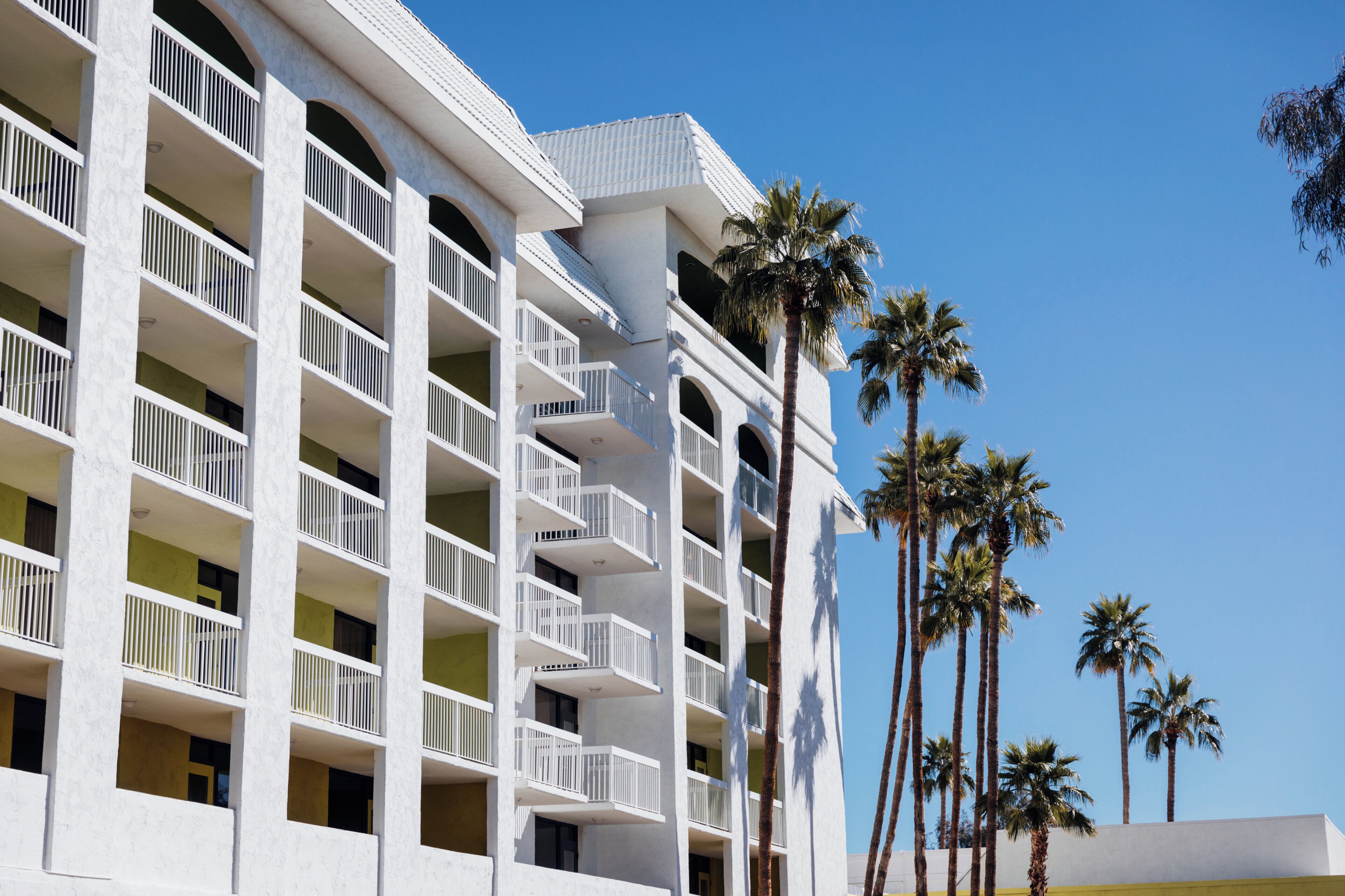 A multi-story hotel with balconies and palm trees.