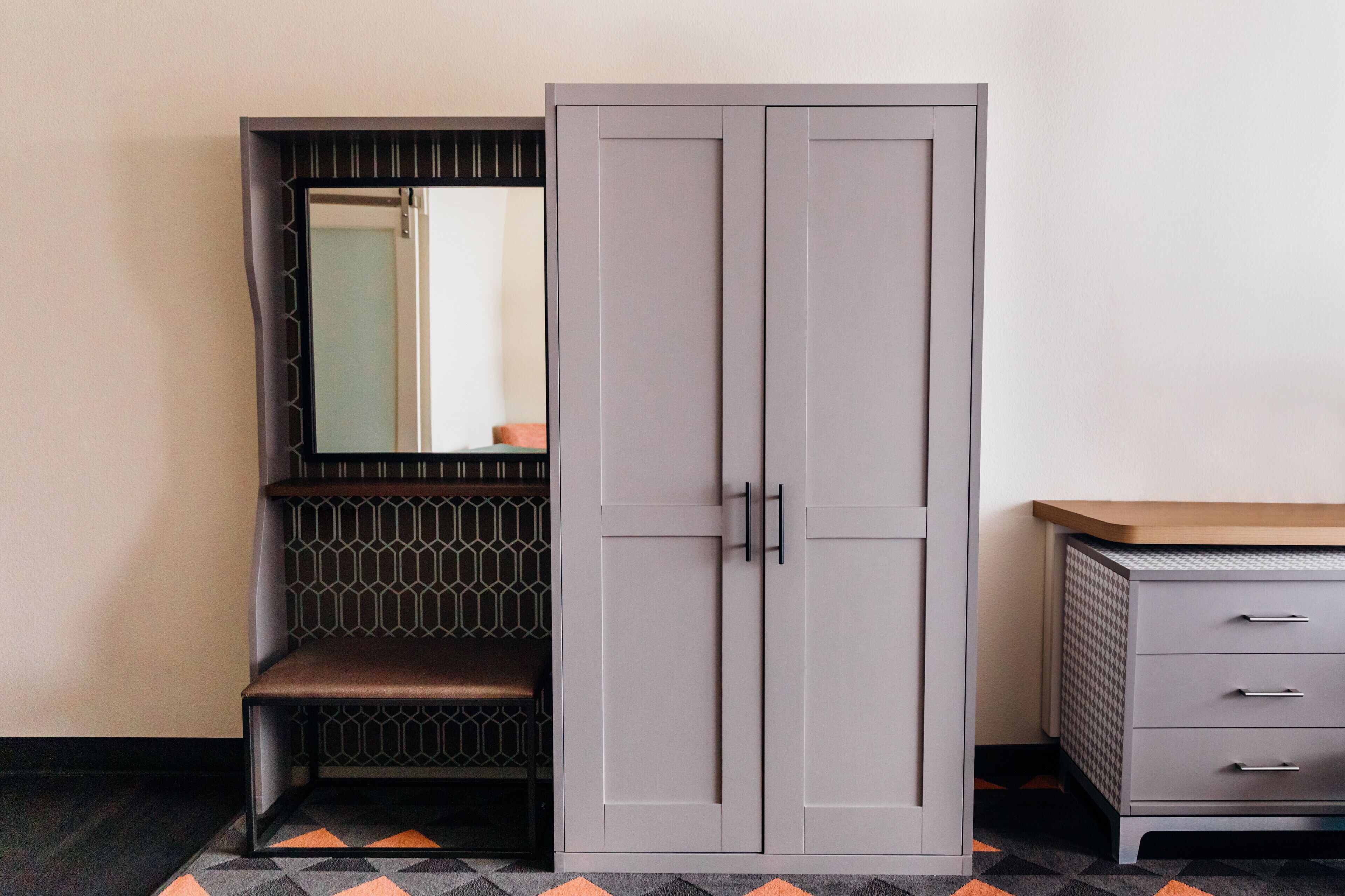 A wardrobe with a mirror, a bench, and a dresser.