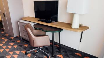 Une chambre d’hôtel équipée d’un bureau, d’une chaise, d’une télévision et d’une lampe.