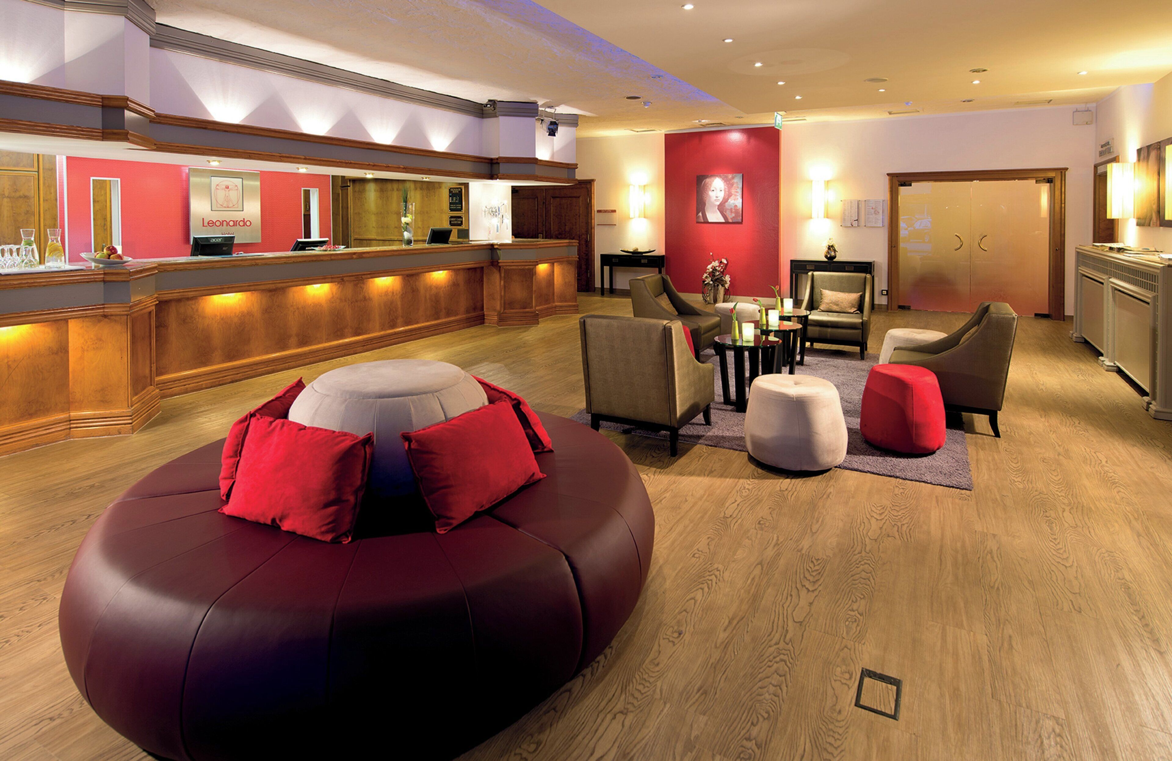 Un hall de hotel con mostrador de recepción, zona de estar y un amplio sofá rojo.