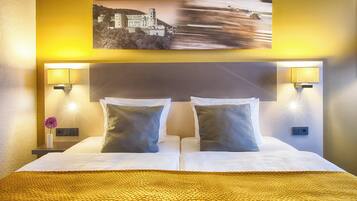 A hotel room with a large bed, two bedside lamps, a nightstand with a vase of flowers, and a picture on the wall.