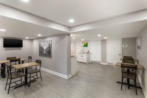 A hotel room with a dining area, a kitchen, and a restroom.
