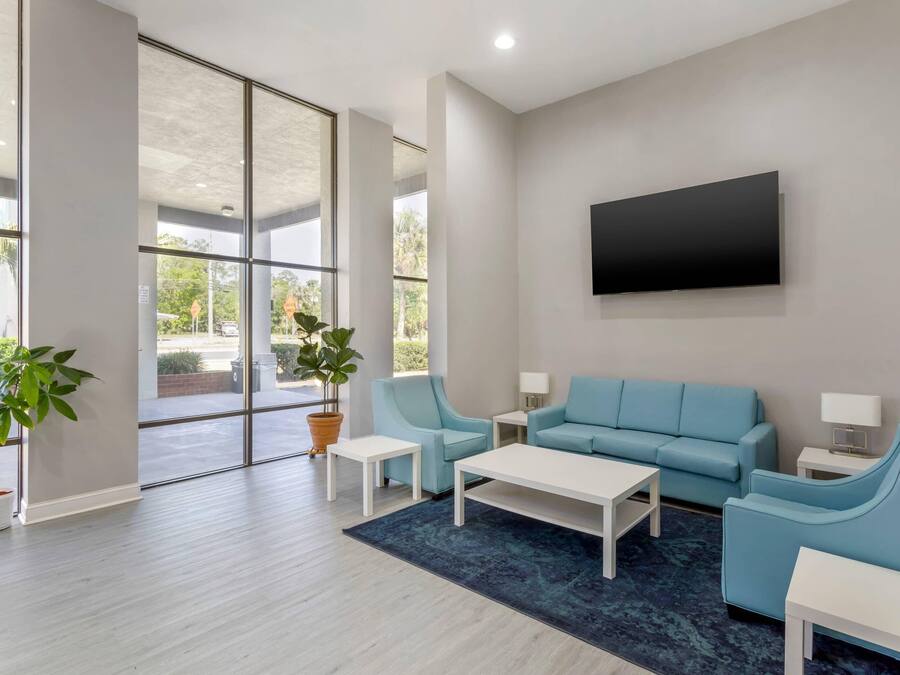 A modern waiting area with a large window, a flat-screen TV, and a blue sofa set.