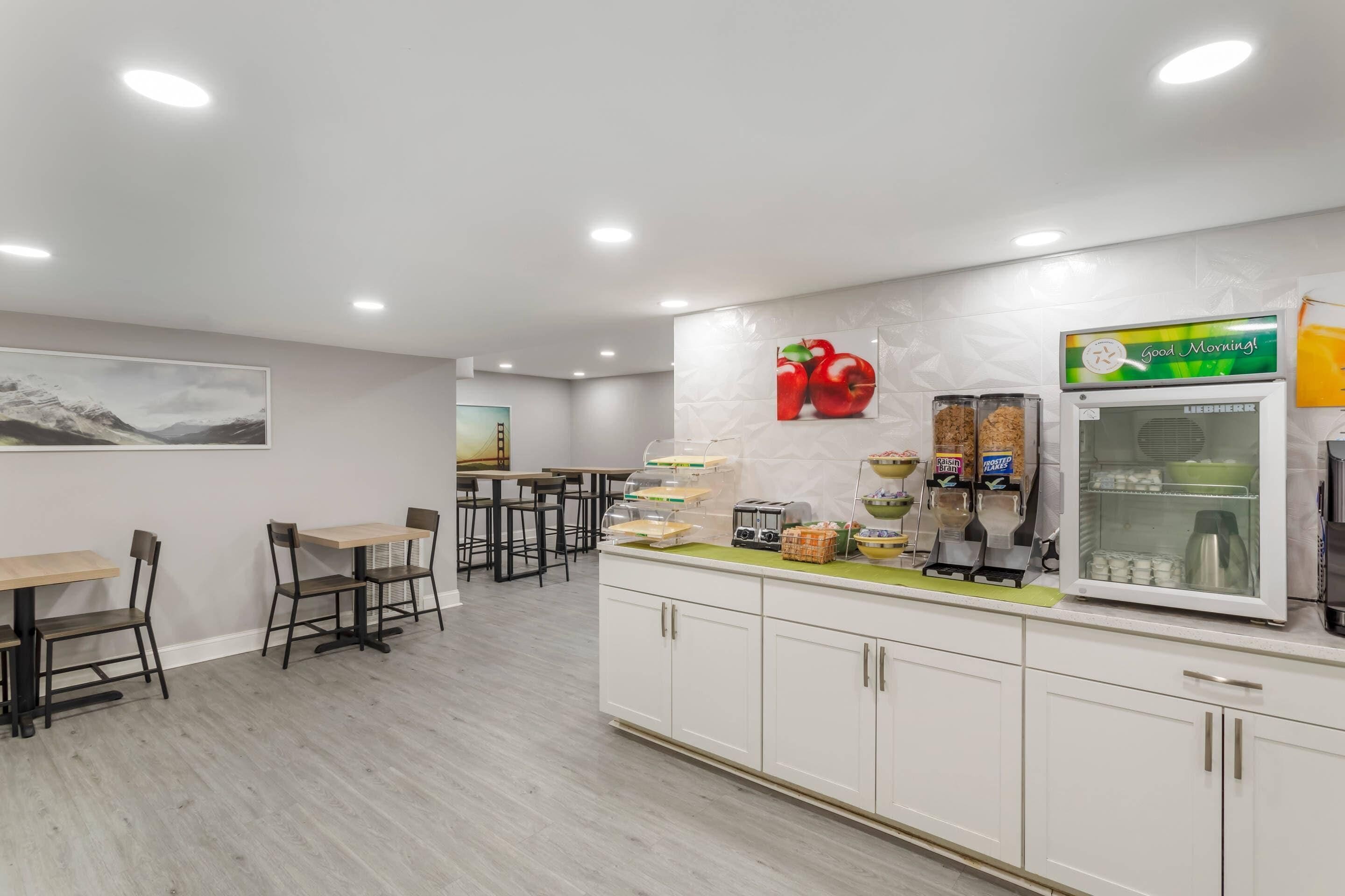 A modern cafe with a counter, seating area, and a refrigerator.