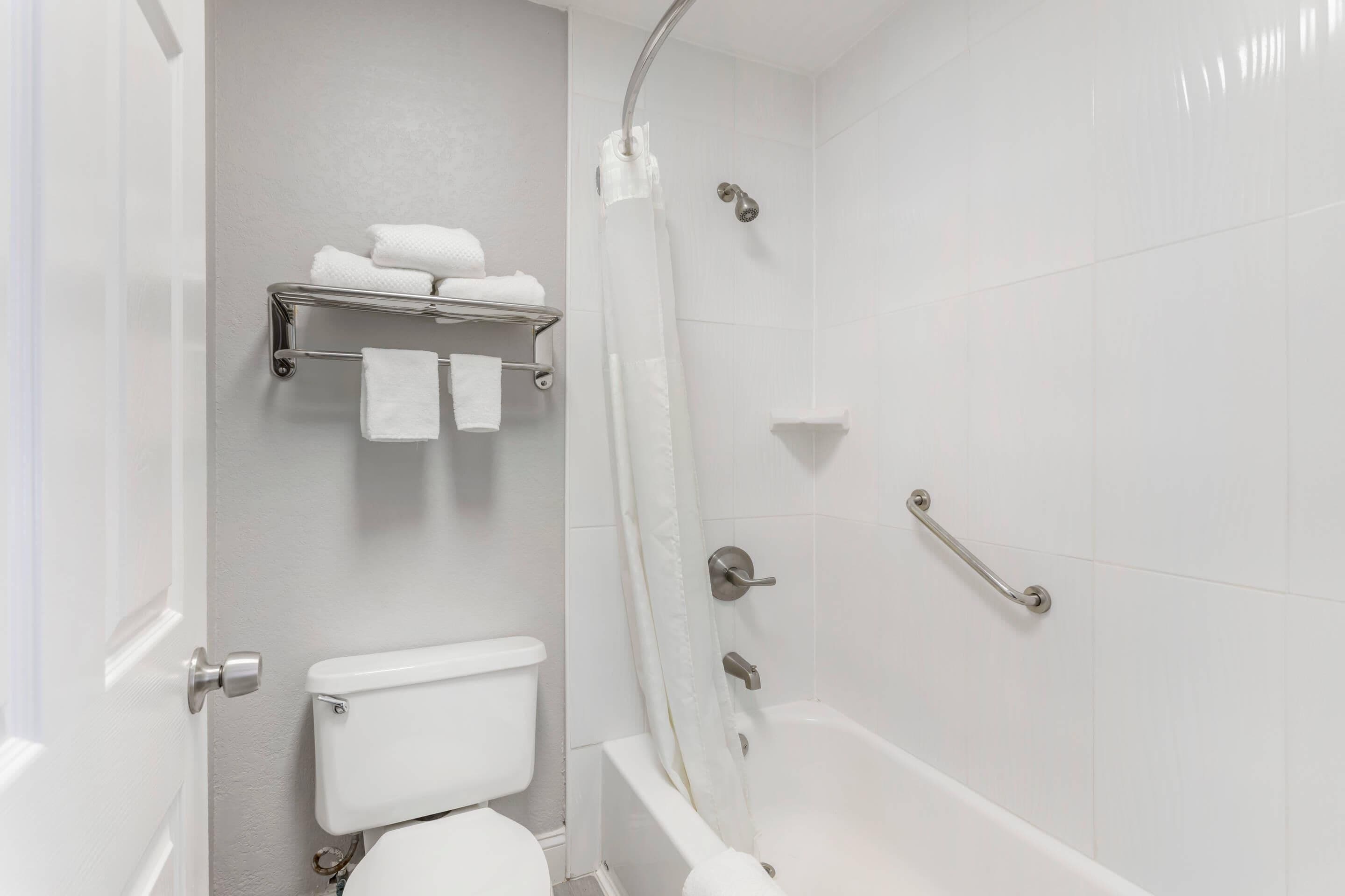 Un baño con inodoro, ducha y barra para toallas.