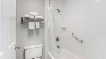 Un baño con inodoro, ducha y barra para toallas.