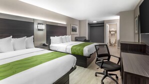 Ein Hotelzimmer mit zwei Betten, einem Schreibtisch, einem Stuhl und einem Badezimmer.