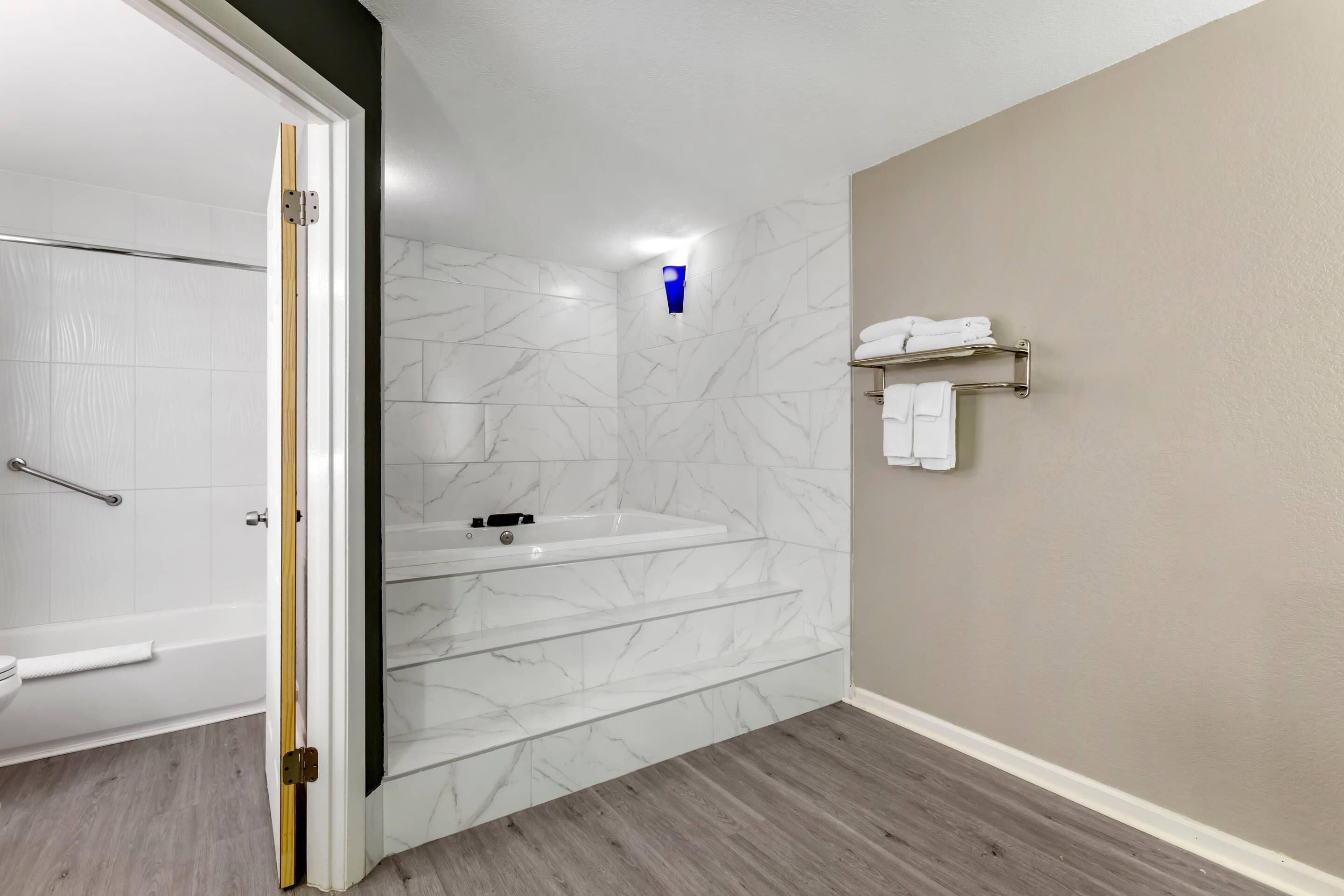 Une salle de bain moderne dotée d’une douche à parois de verre, d’un mur recouvert de carreaux de marbre, d’un lavabo intégré et d’un porte-serviettes.